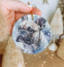 a hand holding a round ornament with a picture of a dog on it