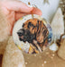 a hand holding a christmas ornament with a picture of a dog