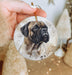 a hand holding a christmas ornament with a picture of a dog
