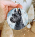 a hand holding a round ornament with a picture of a dog