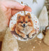a person holding a christmas ornament with a small dog on it