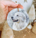 a hand holding a round ornament with a picture of a dog