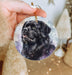 a hand holding a round ornament with a black dog on it