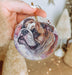 a hand holding a christmas ornament with a dog's face on it