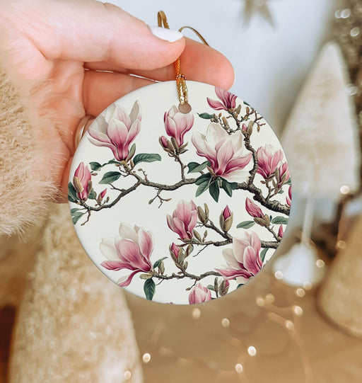 a hand holding a white ornament with pink flowers