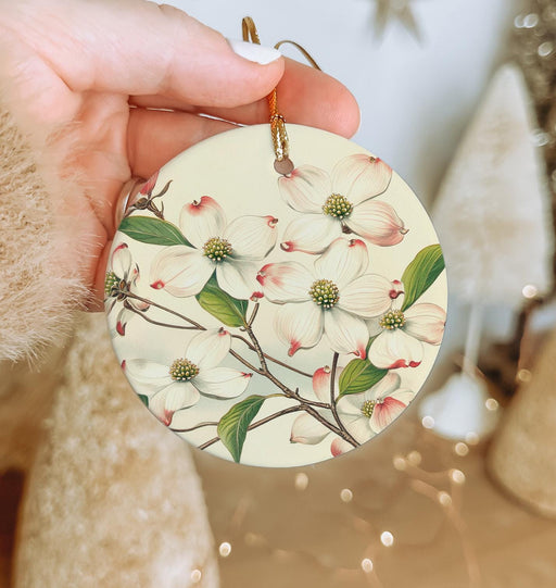 a person holding a christmas ornament with flowers on it