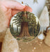 a person holding a christmas ornament with a picture of a tree