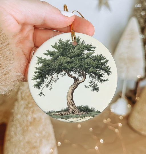 a person holding a christmas ornament with a tree on it