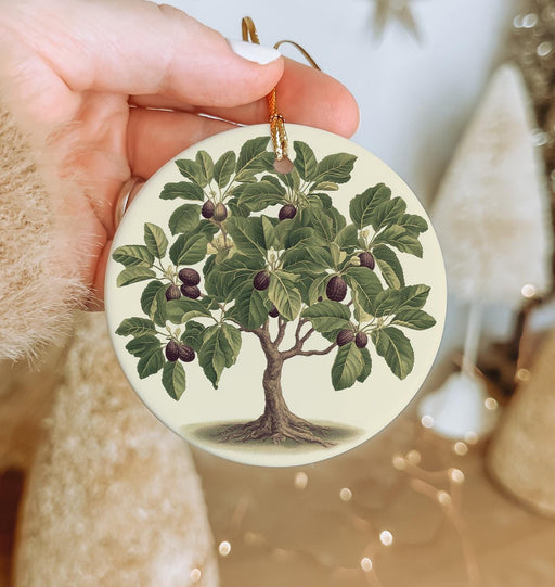 a hand holding a christmas ornament with a tree on it