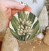 a hand holding a christmas ornament with a picture of a bunch of flowers