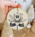 a person holding a ceramic ornament with a flower on it