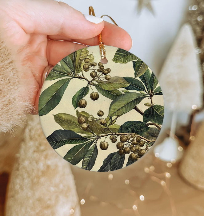 a person holding a christmas ornament with berries and leaves on it