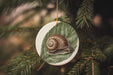 a ceramic ornament with a snail on a leaf