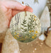 a person holding a round ornament with flowers on it