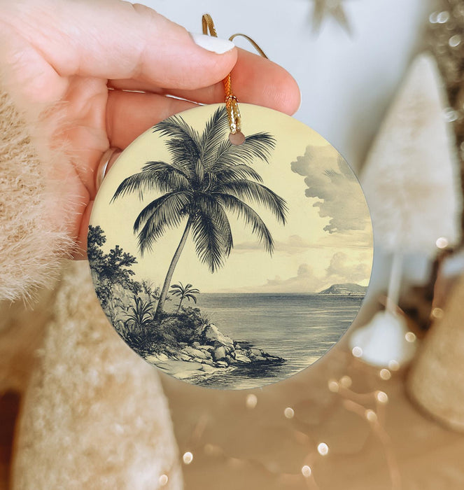 a person holding a christmas ornament with a palm tree on it