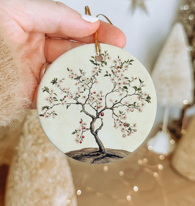 a hand holding a ceramic ornament with a tree on it