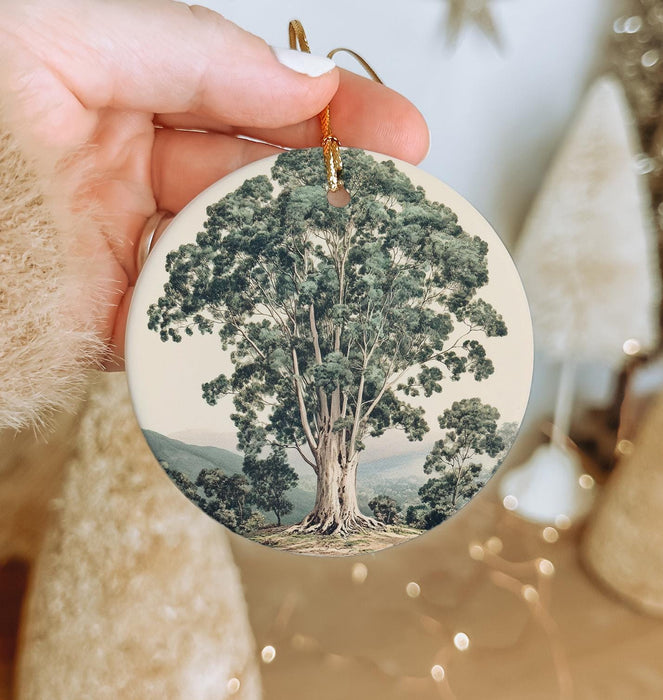 a person holding a christmas ornament with a tree on it