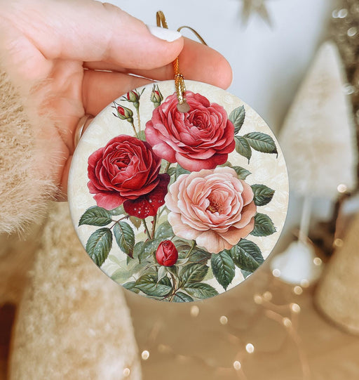 a person holding a christmas ornament with roses on it