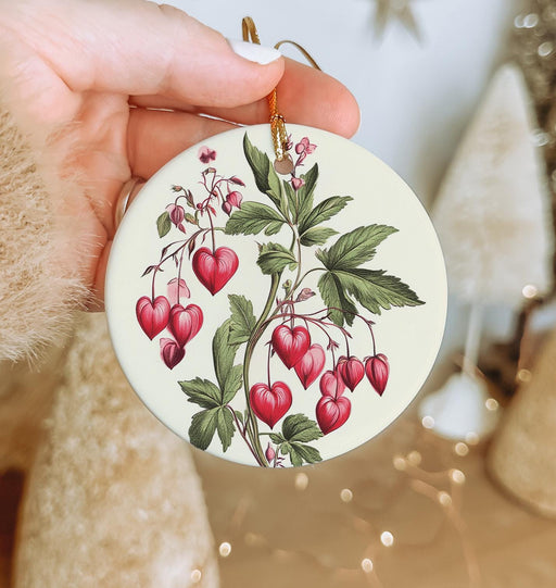 a hand holding a ceramic ornament with cherries on it