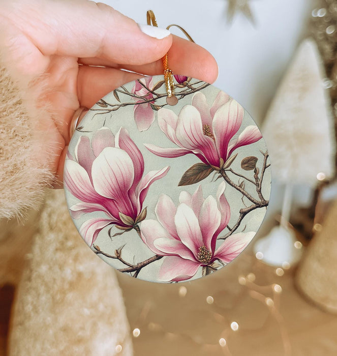 a person holding a christmas ornament with pink flowers on it