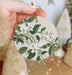 a person holding a white ornament with white flowers on it