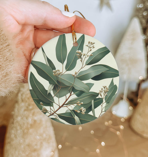 a person holding a round ornament with leaves on it