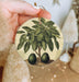 a person holding a christmas ornament with a tree on it