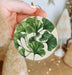 a person holding a green leaf ornament in their hand
