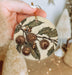a person holding a christmas ornament with a tree in the background
