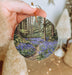 a hand holding a picture of a bluebell forest
