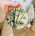 a person holding a round ornament with a bamboo plant on it