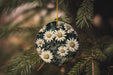 a christmas ornament hanging from a pine tree