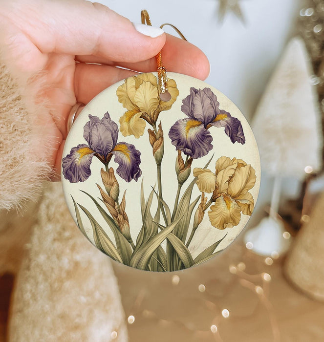 a hand holding a round ornament with flowers painted on it