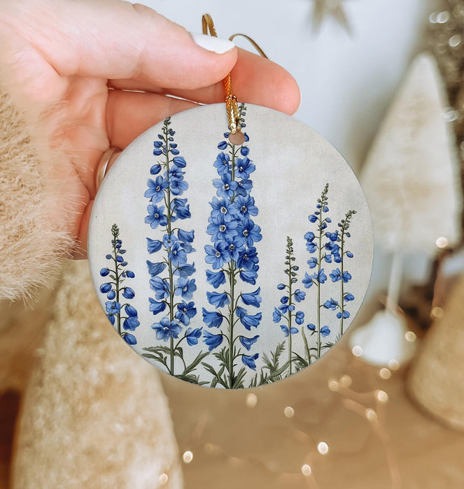 a hand holding a ceramic ornament with blue flowers
