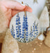 a hand holding a ceramic ornament with blue flowers