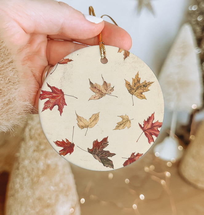 a person holding a christmas ornament with leaves on it