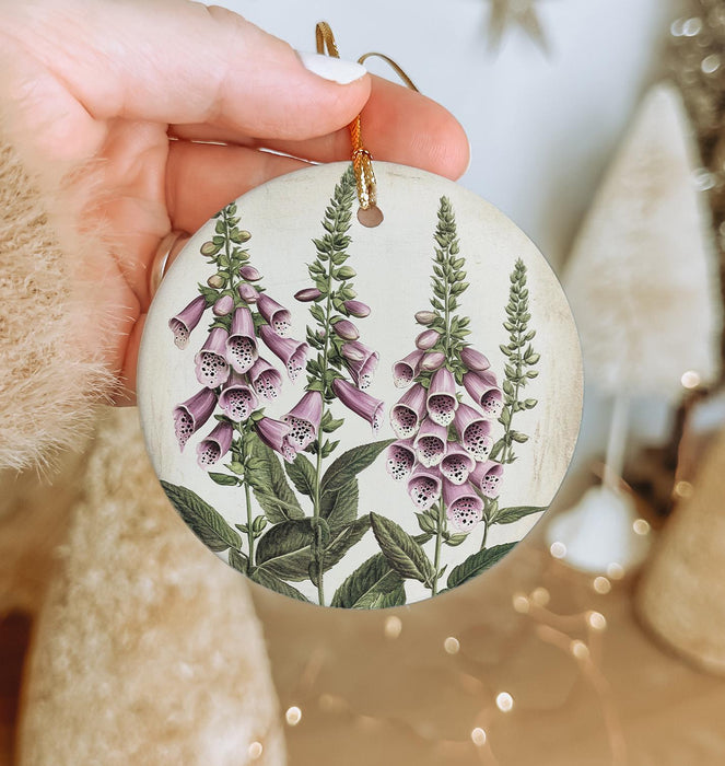a hand holding a ceramic ornament with purple flowers
