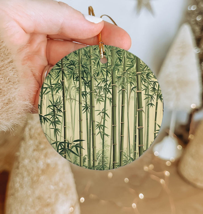 a person holding up a round ornament with bamboo trees on it