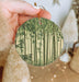 a person holding up a round ornament with bamboo trees on it
