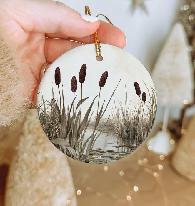 a hand holding a christmas ornament with a painting on it