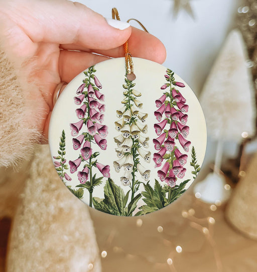 a hand holding a christmas ornament with pink flowers