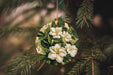 a christmas ornament with white flowers hanging from a tree