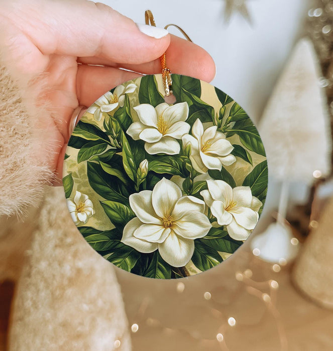 a hand holding a christmas ornament with white flowers