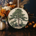 a ceramic ornament with a picture of a pine tree
