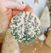 a hand holding a ceramic ornament with a floral design