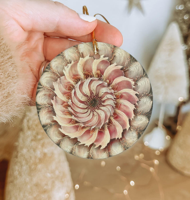 a person holding a christmas ornament with a flower on it