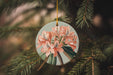 a christmas ornament hanging from a pine tree