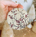 a hand holding a ceramic ornament with berries on it