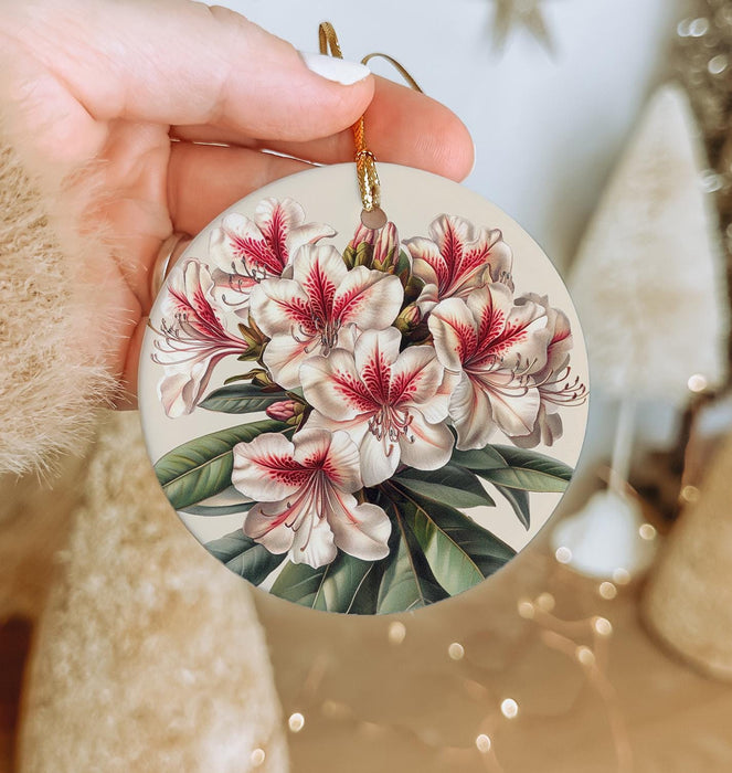 a person holding a christmas ornament with flowers on it