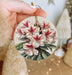 a person holding a christmas ornament with flowers on it